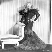 Mae West stoji u crnom dugim haljini s jednom rukom na bok